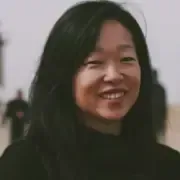 A imagem mostra uma mulher adulta com cabelo comprido e preto, solto, sorrindo suavemente 