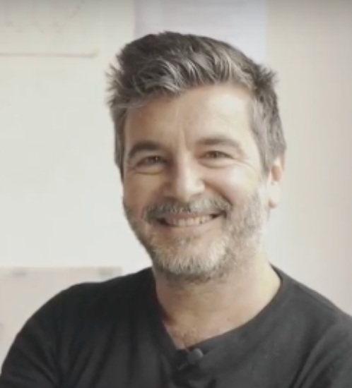 A imagem mostra um homem adulto sorridente, retratado num ambiente interior com luz suave